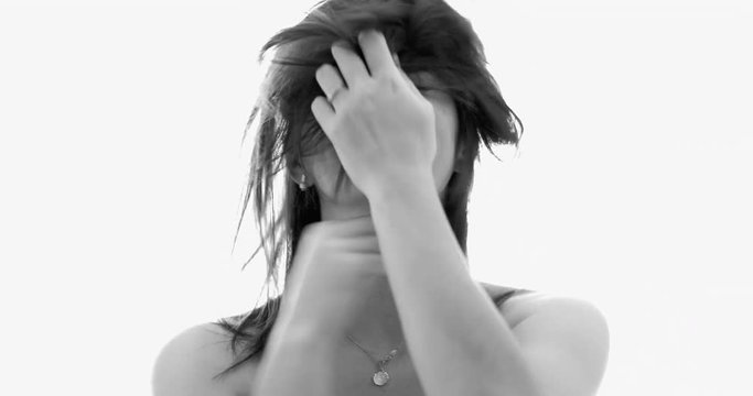 Black and white clip of bashful woman messing up her hair and smiling to camera B&W