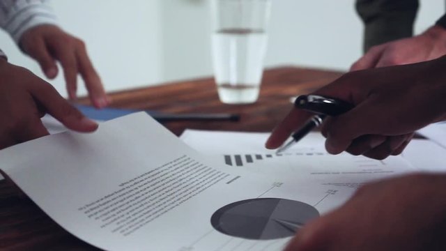 Hands coming together to look at graphs and diagrams about the business growth over the last quater