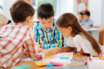 Picture. Concentrated cute children drawing a picture while being in a classroom