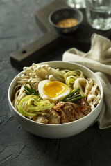 Asian style soup with noodles, egg, meat and mushrooms