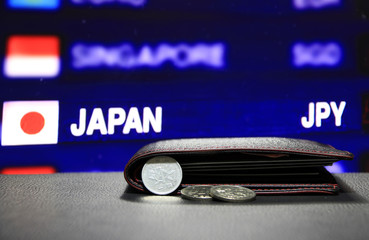 Japanese one Yen coins on obverse (JPY) and pile of other Japanese coins on black floor with black wallet and digital board of currency exchange money background, the concept of finance.