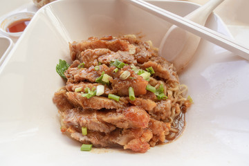 grilled pork roast with yellow or chinese noodle in white a bowl, street food concept