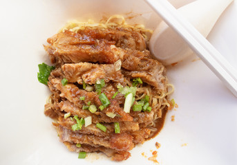 grilled pork roast with yellow or chinese noodle in white a bowl, street food concept