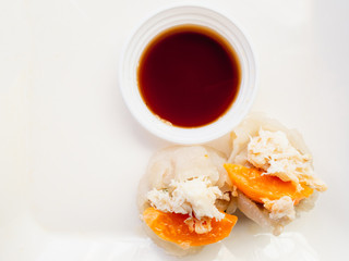 Crab shumai or dim sum, a steamed dish on white plate with black sauce