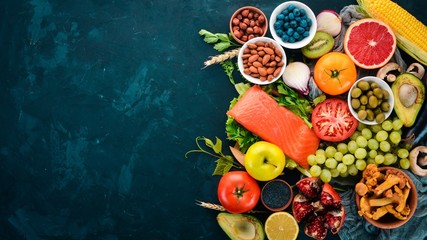 A set of healthy food on a stone table. Fish, vegetables, fruits, nuts, berries, mushrooms. Top view. Free space for text.