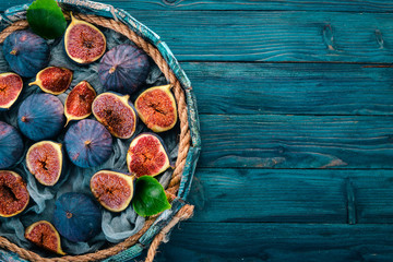 Fresh figs in a wooden box on a blue background. Free space for text. Top view.