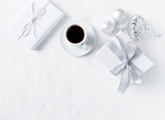 Christmas present, ornaments and a cup of coffee on white painted wooden background. Symbolic image. Flatlay. Copy space