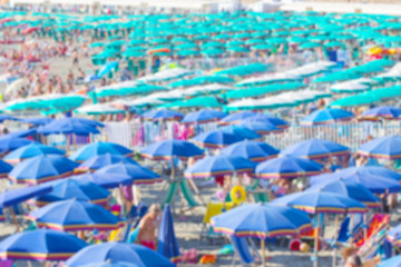 Fototapeta na wymiar Beach scene on a busy summer day with blurred out people, Beach full of people, tourists with umbrella in summer blurred image.