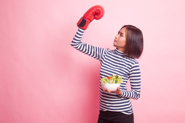 Young Asian woman with boxing glove and salad.