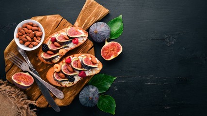 Sandwich with figs, wild berries and cheese. On the old background. Dessert. Free space for text. Top view.