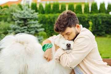 True relief. Dark-haired handsome man kissing his husky feeling relieved while coming and meeting his dog