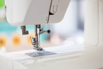sewing machine with colour thread and needle on a table with blurred background, Tailor's work table, textile or fine cloth making, industrial fabric, home appliances tool.