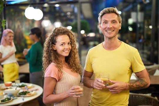 Young cheerful dates cheering up with drinks having fun at party in cafe or restaurant