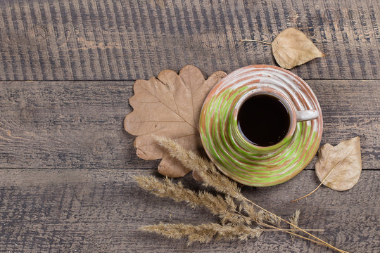 Autumn Composition with coffee cup and full leaves on a wooden table background. Top view.