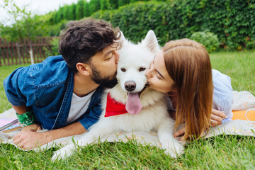 Kissing husky. Couple feeling cheerful while kissing their fluffy husband spending weekend in...