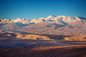 Fototapeta na wymiar Moon Valley in Atacama desert at sunset, snowy Andes mountain range in the background, Chile