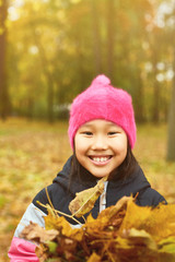 Smiling youngster looking at camera on autumn day in park full of yellow leaves