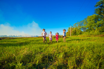 Fototapeta na wymiar Group of happy kids running in green summer field