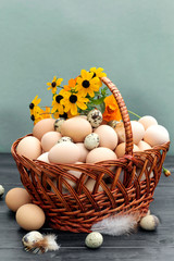 Chicken eggs and quail eggs in basket on wooden background.