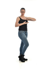 full length portrait of brunette girl wearing black single and jeans. standing pose facing the camera. isolated on white studio background.