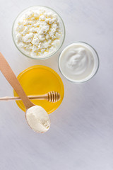 Dairy products and honey with wooden cutlery. Cottage cheese, sour cream, cream on a white background top view. Different organic products for vegan. Healthy food