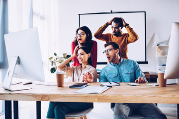 shocked multiracial business team working on project together in office