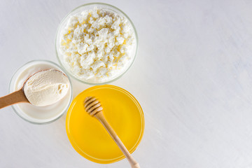 Dairy products and honey with wooden cutlery. Cottage cheese, sour cream, cream on a white background top view. Different organic products for vegan. Healthy food
