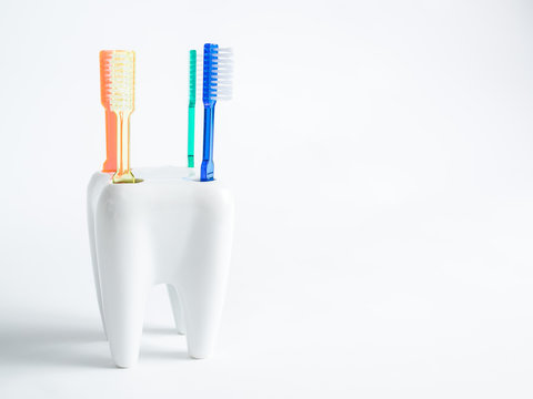 4 colored toothbrushes stand in glass, concept dental, The toothbrushes stand in a porcelain mug that looks like a tooth, picture for appointment cards