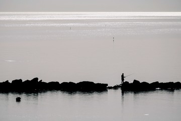 Silhouette di un pescatore sulla scogliera