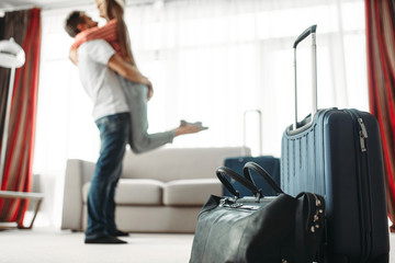 Suitcases prepared for vacation, happy couple hugs