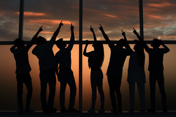 business team pointing through a large office window to blank space