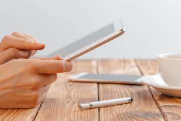 Close-up of young female hands holding digital tablet and drinking morning macchiato.