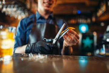 Bartender cut rind from oranges at the bar counter