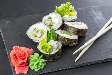 Japanese restaurant, sushi roll on black slate plate.