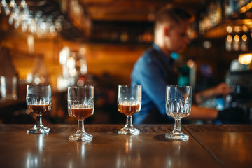 Glasses on bar counter, bartender on background