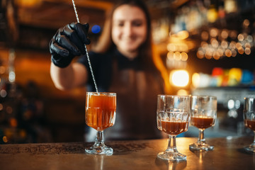Female bartender making coctail at the bar counter