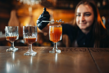 Female bartender prepares alcoholic coctail in pub