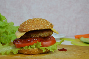 Home made hamburger with beef, onion, tomato, lettuce and cheese. Fresh burger closeup on wooden rustic table