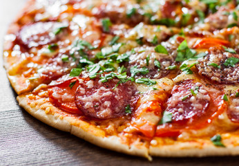 sliced Pepperoni Pizza with Mozzarella cheese, salami, Tomatoes, pepper, Spices and Fresh Basil. Italian pizza on wooden background