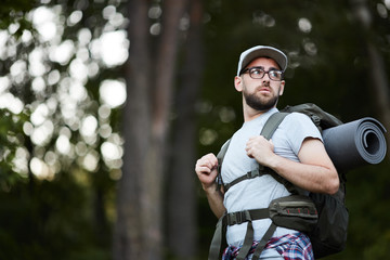 Obraz premium Young man wearing eyeglasses in backpack travelling through the forest