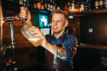 Male barman pouring beer at the bar counter