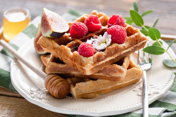 Belgian waffles with raspberries, honey and figs on a plate. Closeup view. Morning breakfast food photography