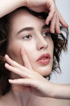 Closeup beauty portrait of young woman with hands near face