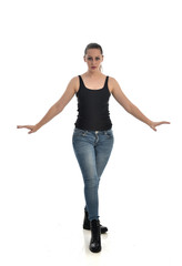 full length portrait of brunette girl wearing black single and jeans. standing pose facing the camera. isolated on white studio background.