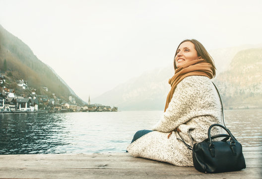 Tourist woman sits near the Hallstatt lake