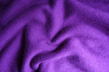 Fototapeta na wymiar Soft folds on bright violet knitted fabric