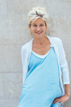Mature blonde smiling woman wearing blue dress