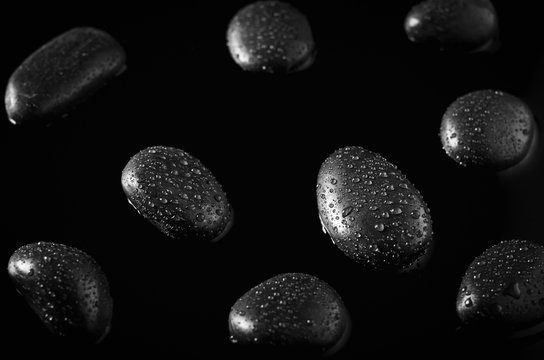 Close up of water drops at black stones on black water background