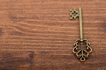 Old vintage key on a wooden background.