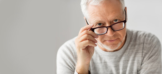 old age, problem and people concept - close up of senior man in glasses thinking